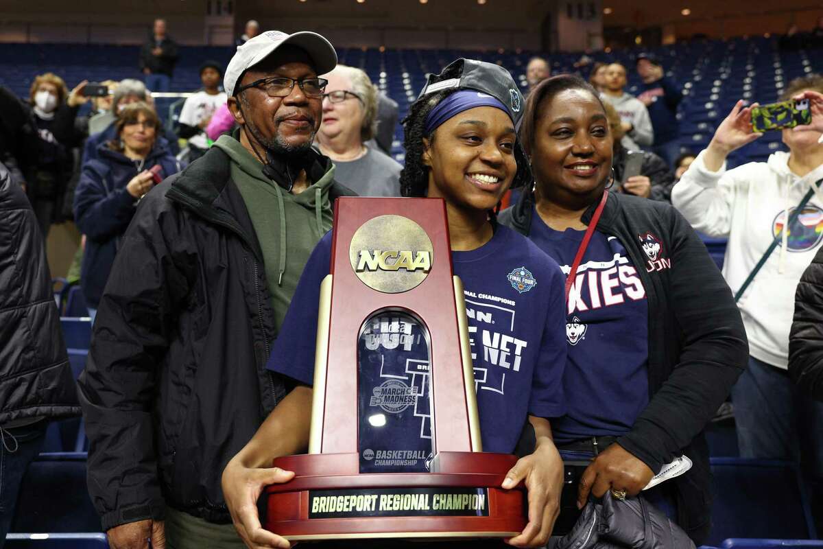 BRIDGEPORT, CONNECTICUT - MARCH 28: Christyn Williams #13 of the UConn Huskies poses for a photo with her parents after defeating the NC State Wolfpack 91-87 in 2 OT in the NCAA Women's Basketball Tournament Elite 8 Round at Total Mortgage Arena on March 28, 2022 in Bridgeport, Connecticut. (Photo by Elsa/Getty Images)