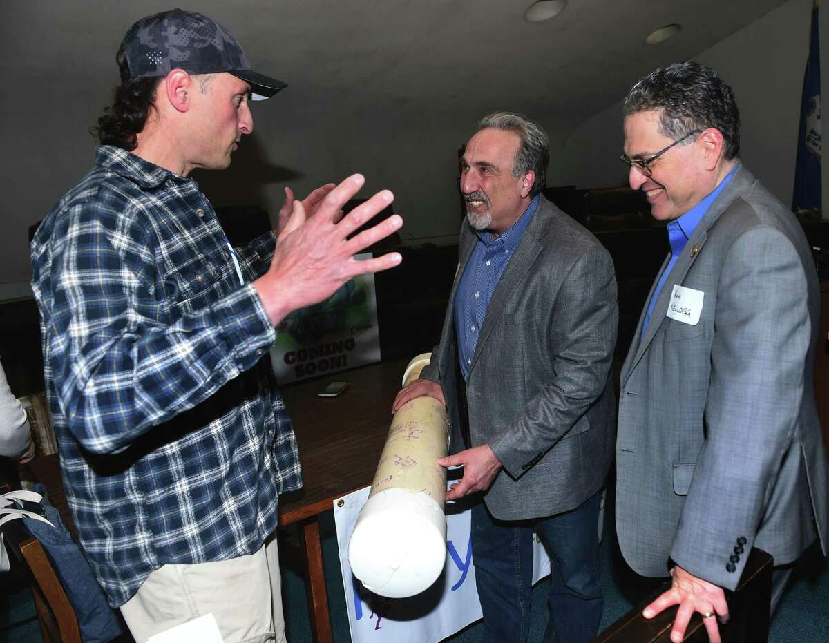 From left, Keith Romano, committee member of the Monroe Playground Foundation, Mike Ganino, vice chair of the Board of Directors of the Monroe Playground Foundation, and First Selectman Ken Kellogg look over the time capsule from the Kids Kreations playground at Monroe Town Hall on March 29, 2022.