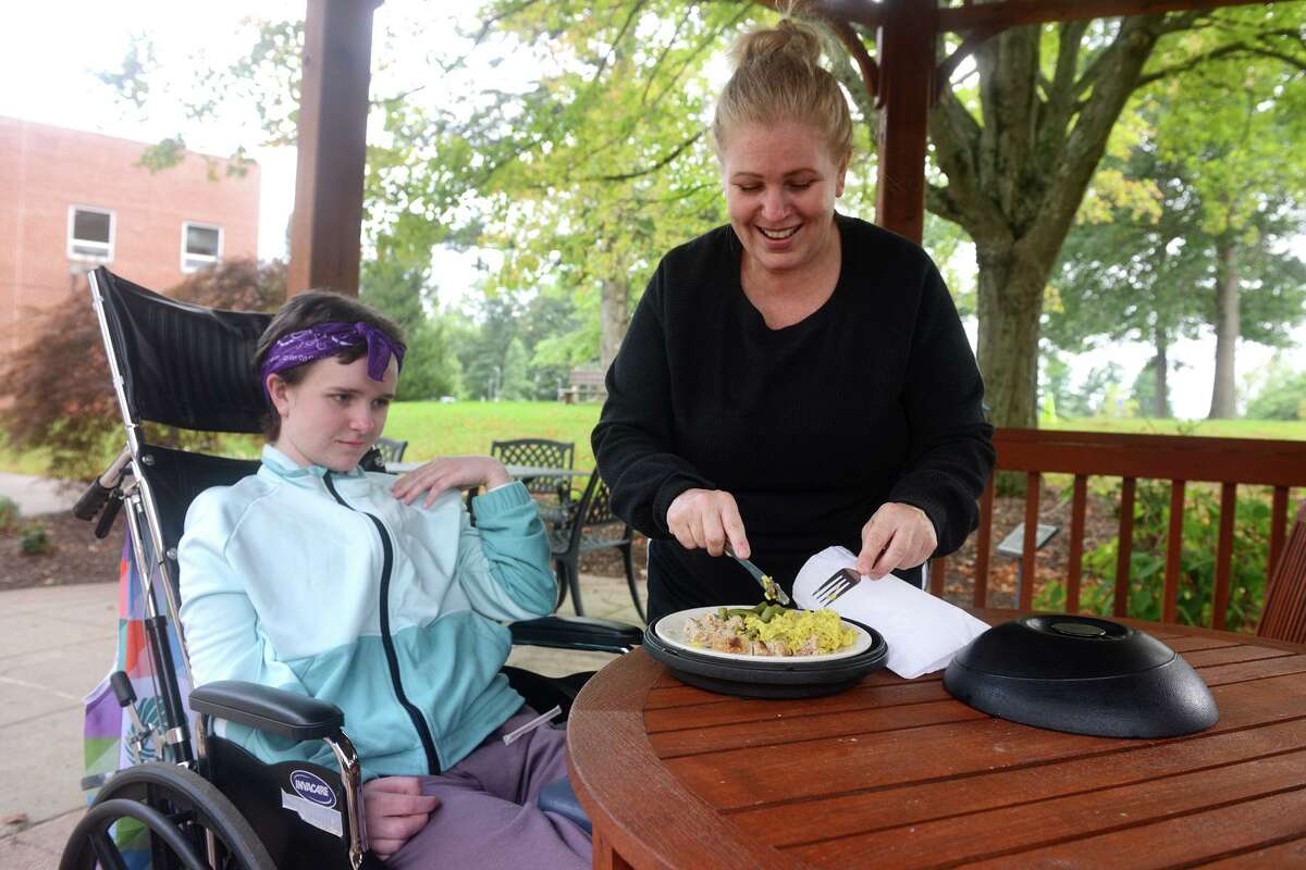 Elizabeth Gower helps her daughter Eva Houlihan with her dinner at Gaylord Hospital/Specialty Healthcare, in Wallingford, Conn. Sept. 24, 2021. Eva is recovering from a car accident in Southbury last April that left her boyfriend dead.