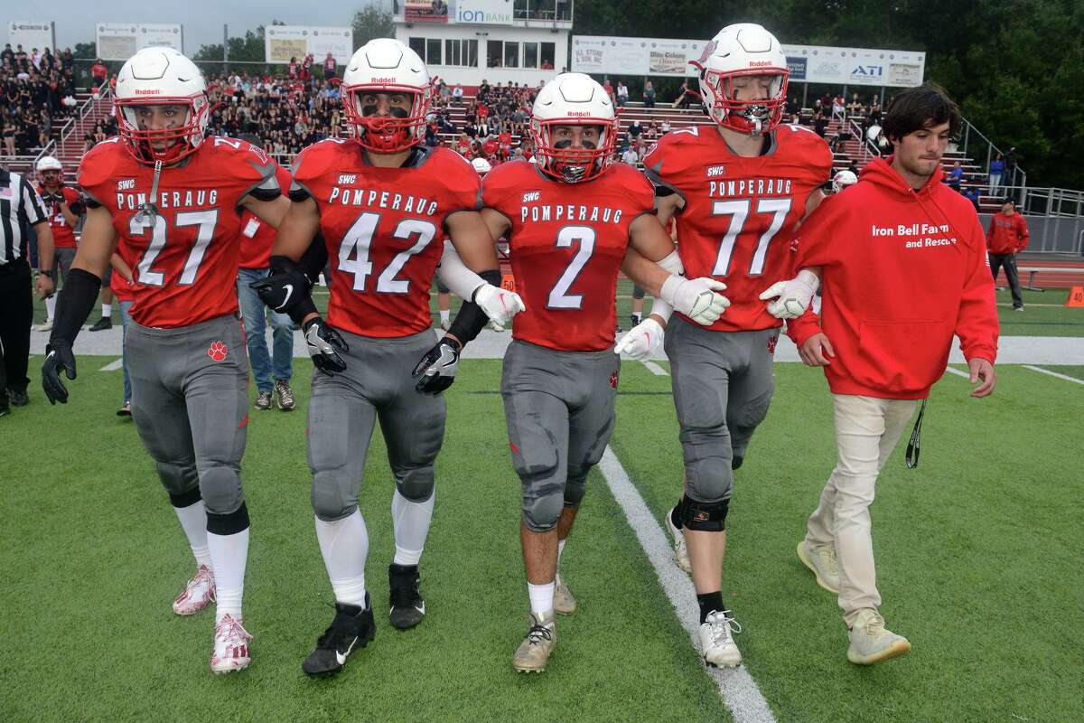 Patrick Rutledge, right, Ryan Rutledge’s twin brother walks with members of the Pomperaug High School football as they approach for the coin toss before a game against Bunnell High School, in in Southbury, Conn. Sept. 17, 2021. Ryan Rutledge, who was a member of the Pomperaug football team, was killed in an automobile accident in April.