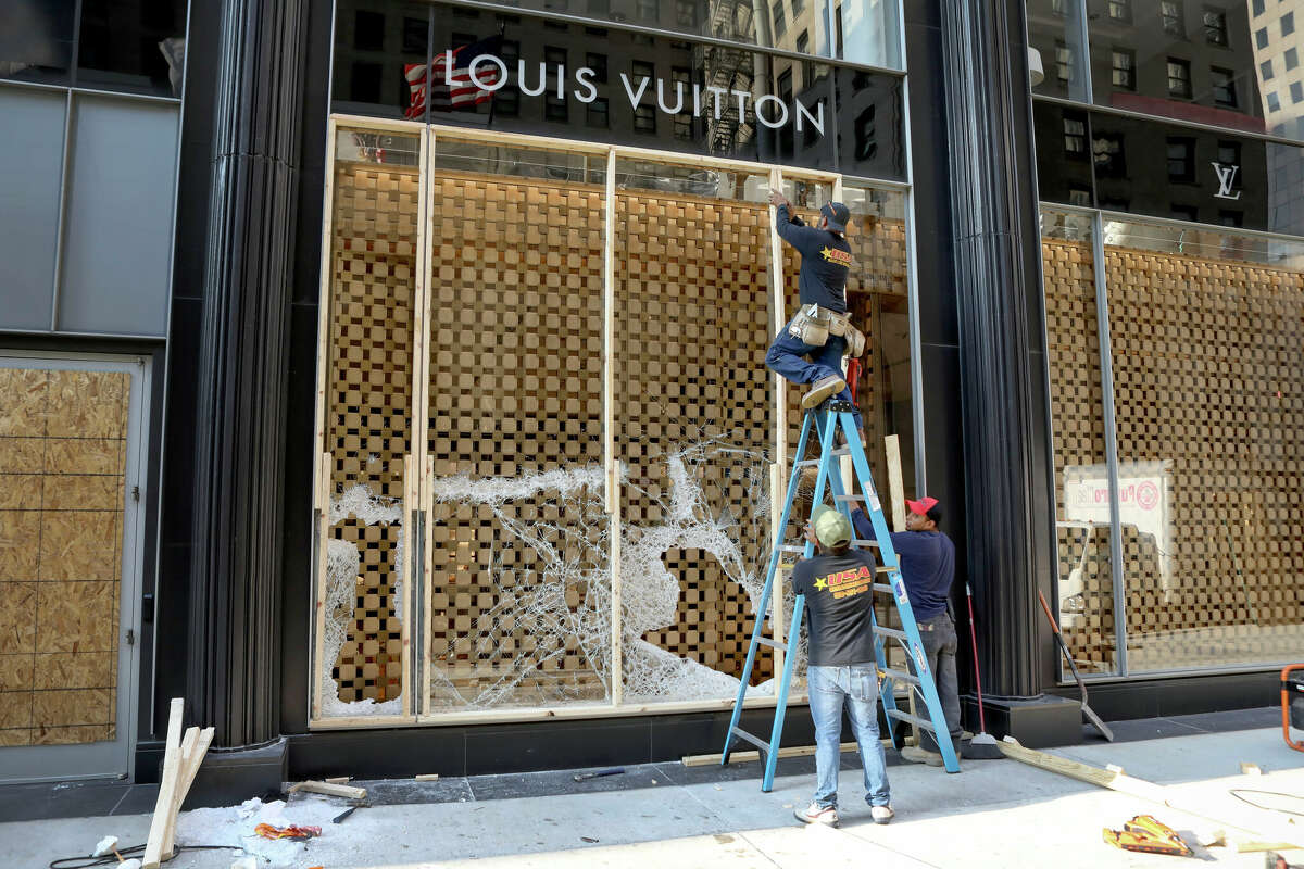 Workers board up a display window at the Louis Vuitton store in 2020 after vandals hit high-end shops in Chicago. The state Senate has a bipartisan plan to crack down on a recent spate of smash-and-grab retail thefts and the fencing of the items that follows.