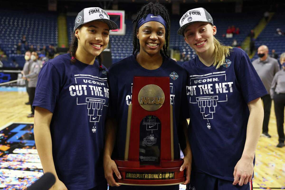 BRIDGEPORT, CONNECTICUT - MARCH 28: (L-R) Azzi Fudd #35, Evina Westbrook #22, and Paige Bueckers #5 of the UConn Huskies pose with the regional champions trophy after defeating the NC State Wolfpack 91-87 in 2 OT in the NCAA Women's Basketball Tournament Elite 8 Round at Total Mortgage Arena on March 28, 2022 in Bridgeport, Connecticut. (Photo by Elsa/Getty Images)