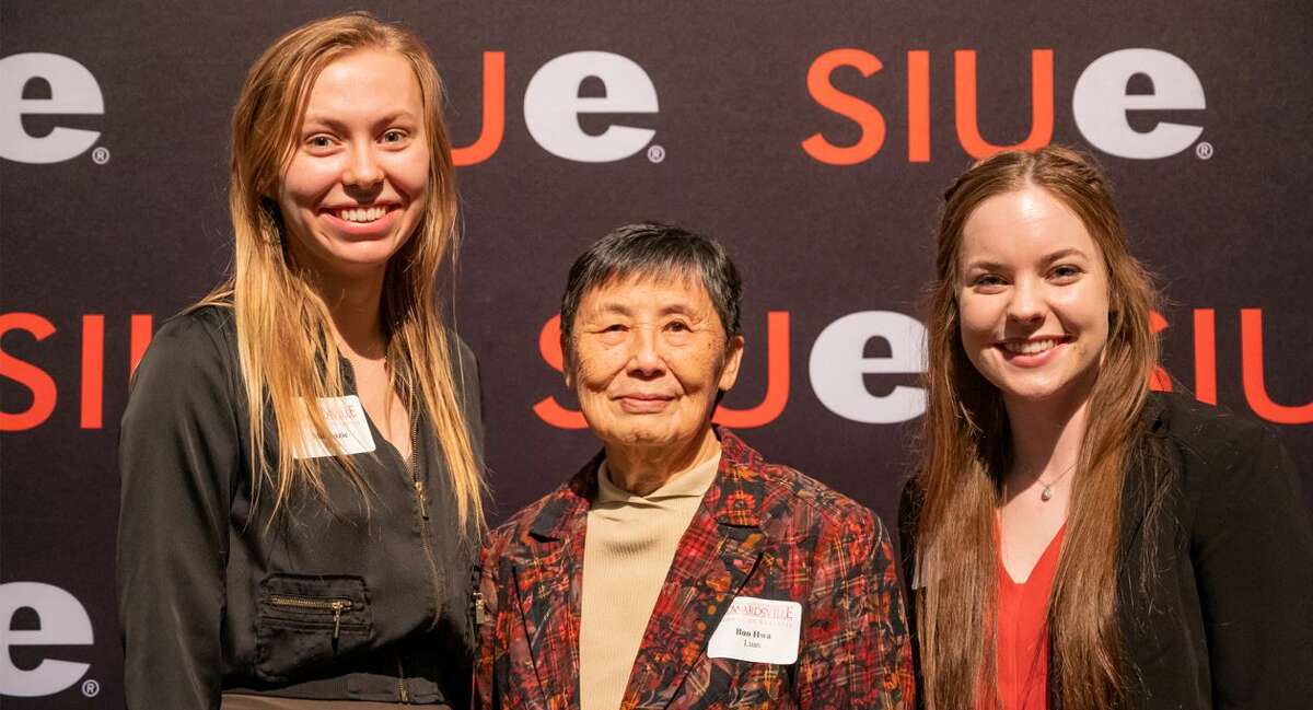Scholarship recipients Mickenzie Bass, left, and Kelly Cruise, right, stand with Buo Hwa Luan.