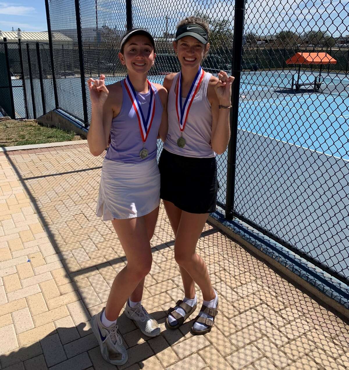Midland High senior Montserrat Salazar, left, and junior Sarah Stewart pose with their medals after finishing second and first at the District 2-6A Tennis Tournament, March 31 in San Angelo. 