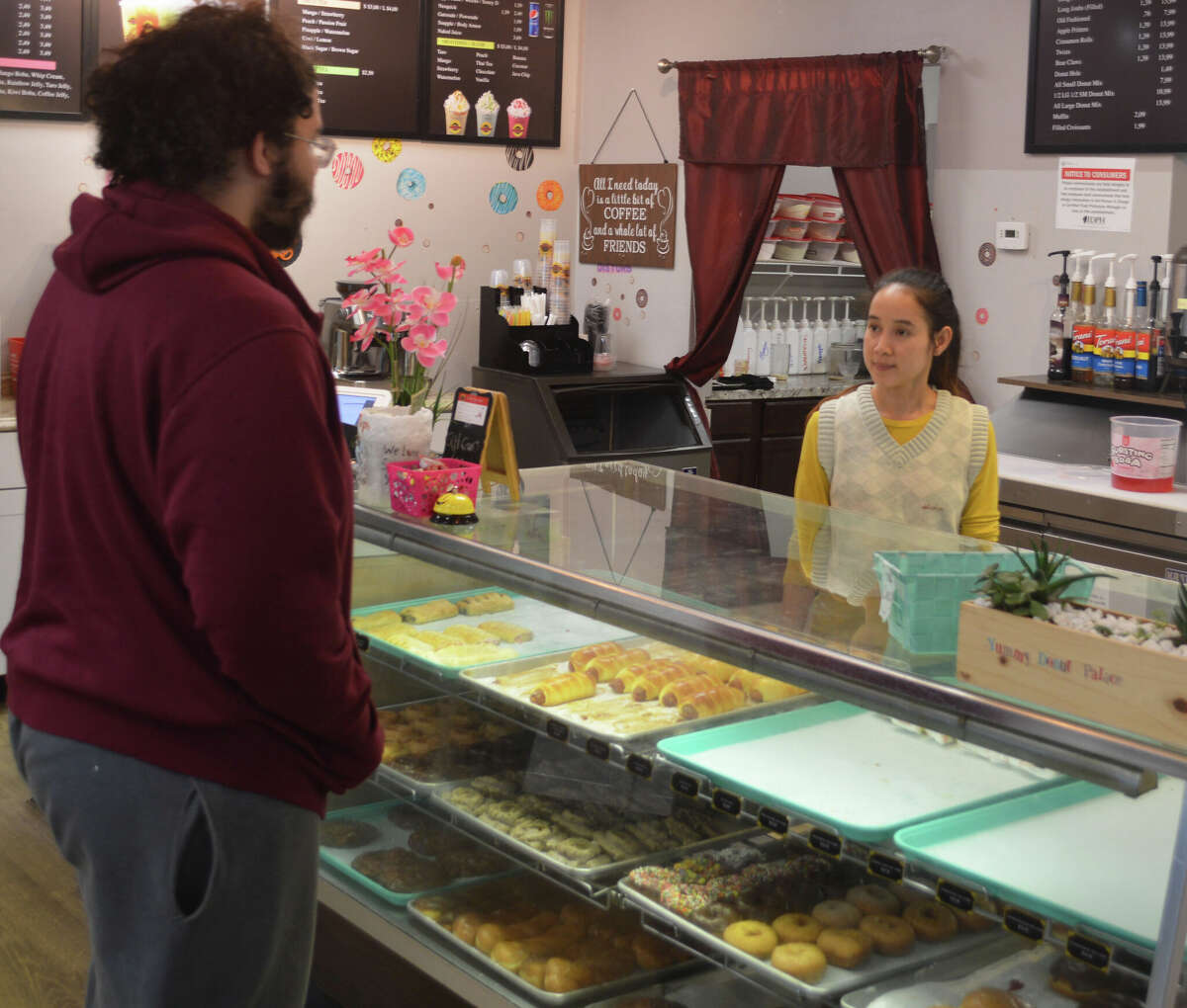 Akara Thap, right, owner of Yummy Donut Palace, serves Roberto Griffith, who is a regular customer of the location in Edwardsville. Like many local small businesses, Yummy Donut Palace has had to raise prices due to inflation.