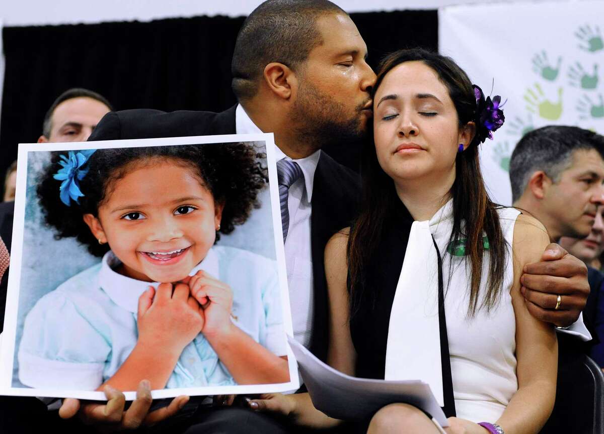Jimmy Greene, left, kisses his wife Nelba Marquez-Greene as he holds a portrait of their daughter, Sandy Hook School shooting victim Ana Grace Marquez-Greene, at a news conference in Newtown, Conn, in 2013.