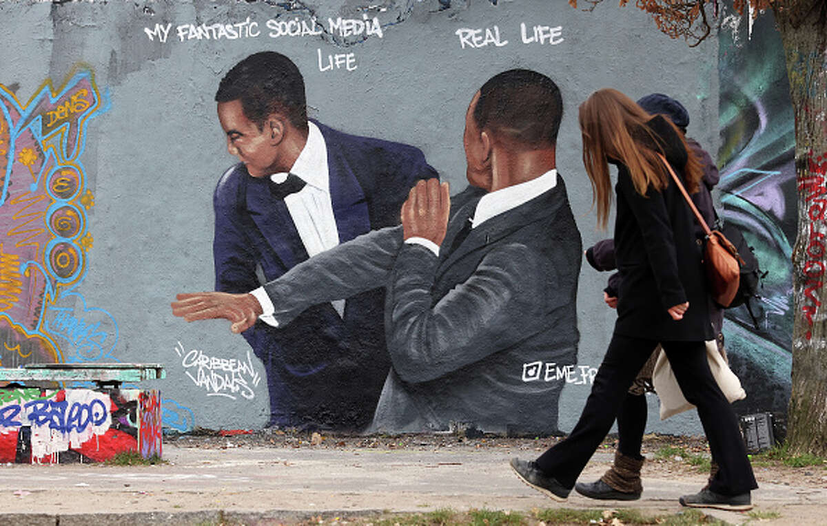 Graffiti depicting a meme showing actor Will Smith slapping comedian Chris Rock criticizes idealized self-portrayals of social media users' lives.