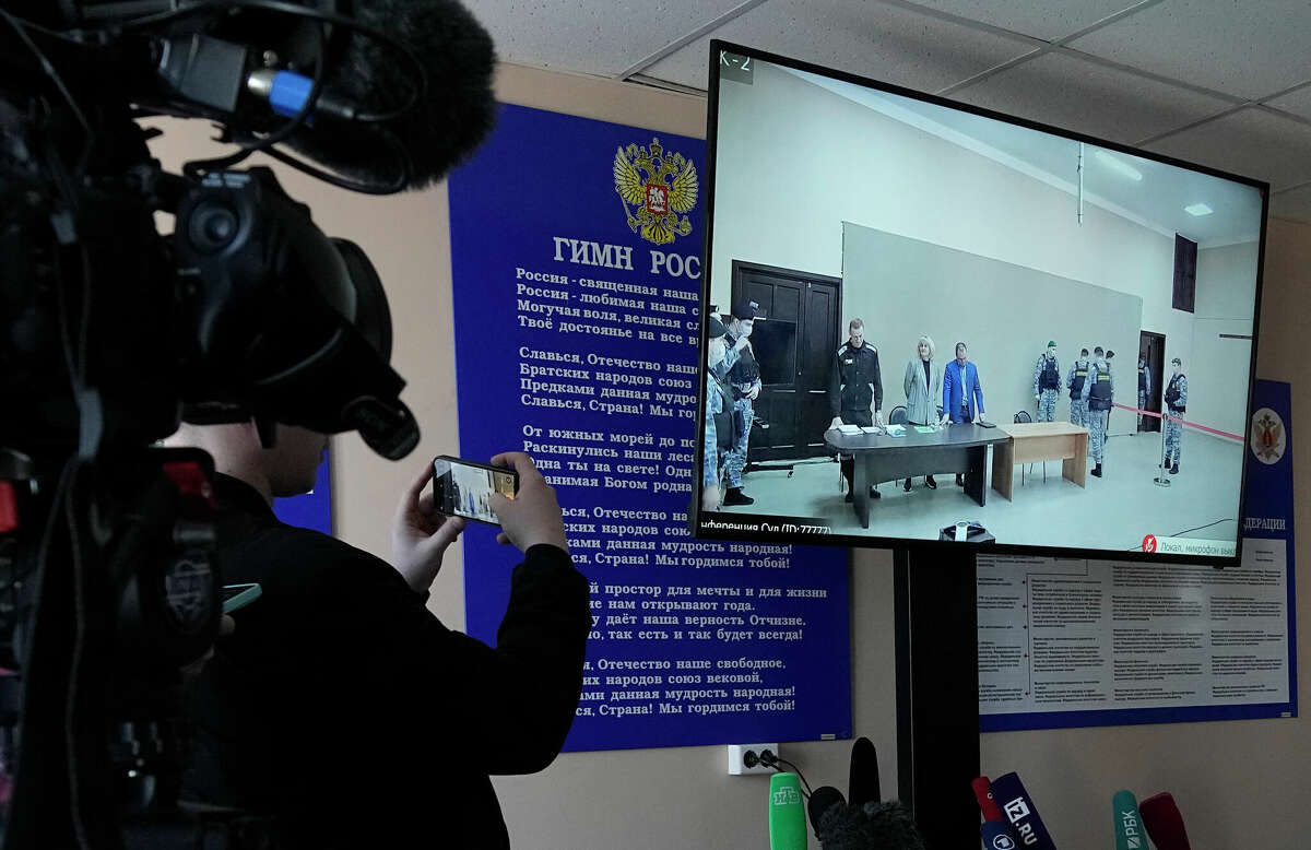 Journalists film a TV screen translating a court session of Russian opposition leader Alexei Navalny, in Pokrov, Vladimir region, east of Moscow, Russia, March 22, 2022. 