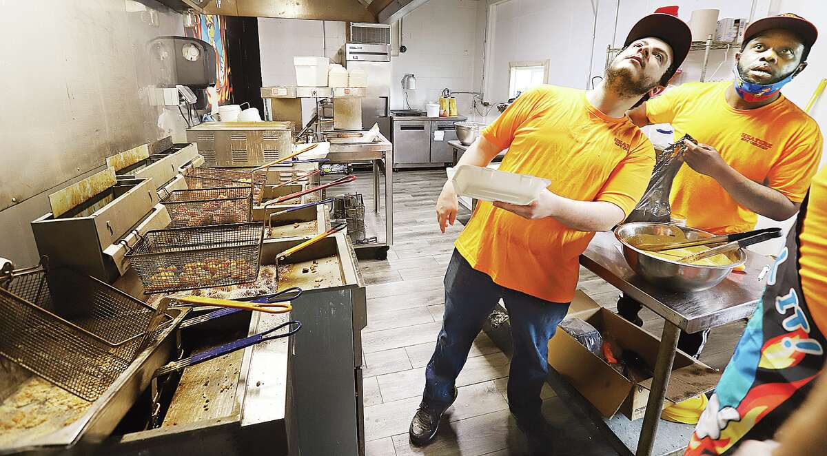 John Badman|The Telegraph Brian Benham, left, and Darius Redd look up at the orders being posted during the lunch hour rush when Heaterz Hot Chicken opened in March at the corner of Main and Brown streets in Alton. On Monday, the restaurant's request for a video gambling license failed.