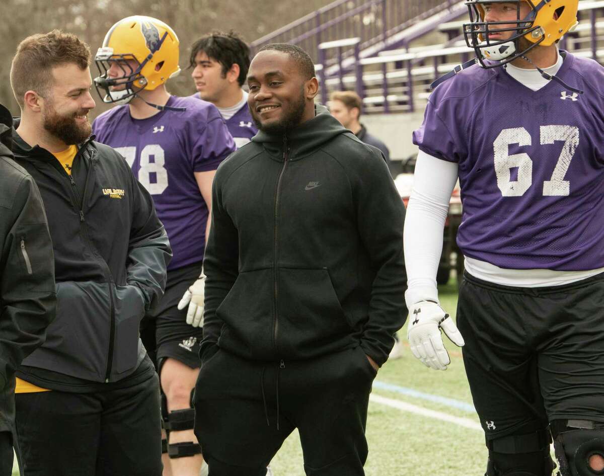 Former University at Albany football player Karl Mofor, center, is seen visiting with players and coaches as the UAlbany football team practices at Casey Stadium on Friday, April 1, 2022 in Albany, N.Y.