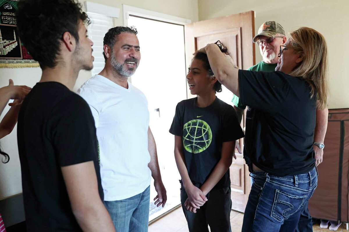 Iraqi immigrant Abdul Abdallah, 45, center in white T-shirt, smiles as long-time friend Pam Allen, right, jokes with his son, Dheyaa, 13, at his home Friday, March 18. Abdallah served as an interpreter for the US Army for five years.  He and his family immigrated to the US in 2010. Since then, he's acted as a calming force in the North Side refugee community, helping resettlement caseworkers tend to the needs of immigrants from around the world.  With them are his eldest son, Bahaulldin, 16, left, and Allen's husband, Tim.
