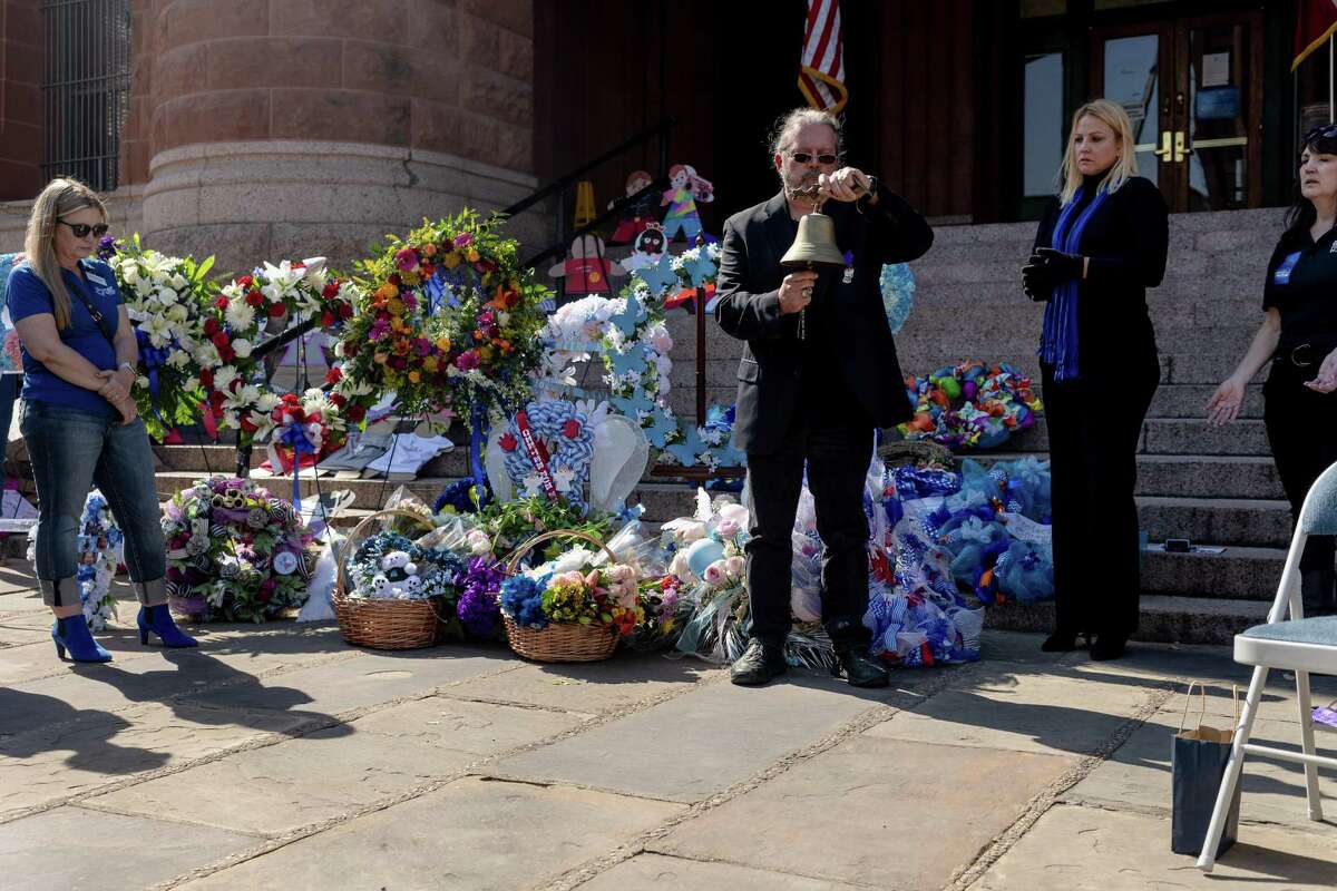 A bell is rung during a wreath-laying ceremony at the Bexar County Courthouse to recognize the 13 local child deaths that occurred last year and mark the beginning of National Child Abuse Prevention Month.