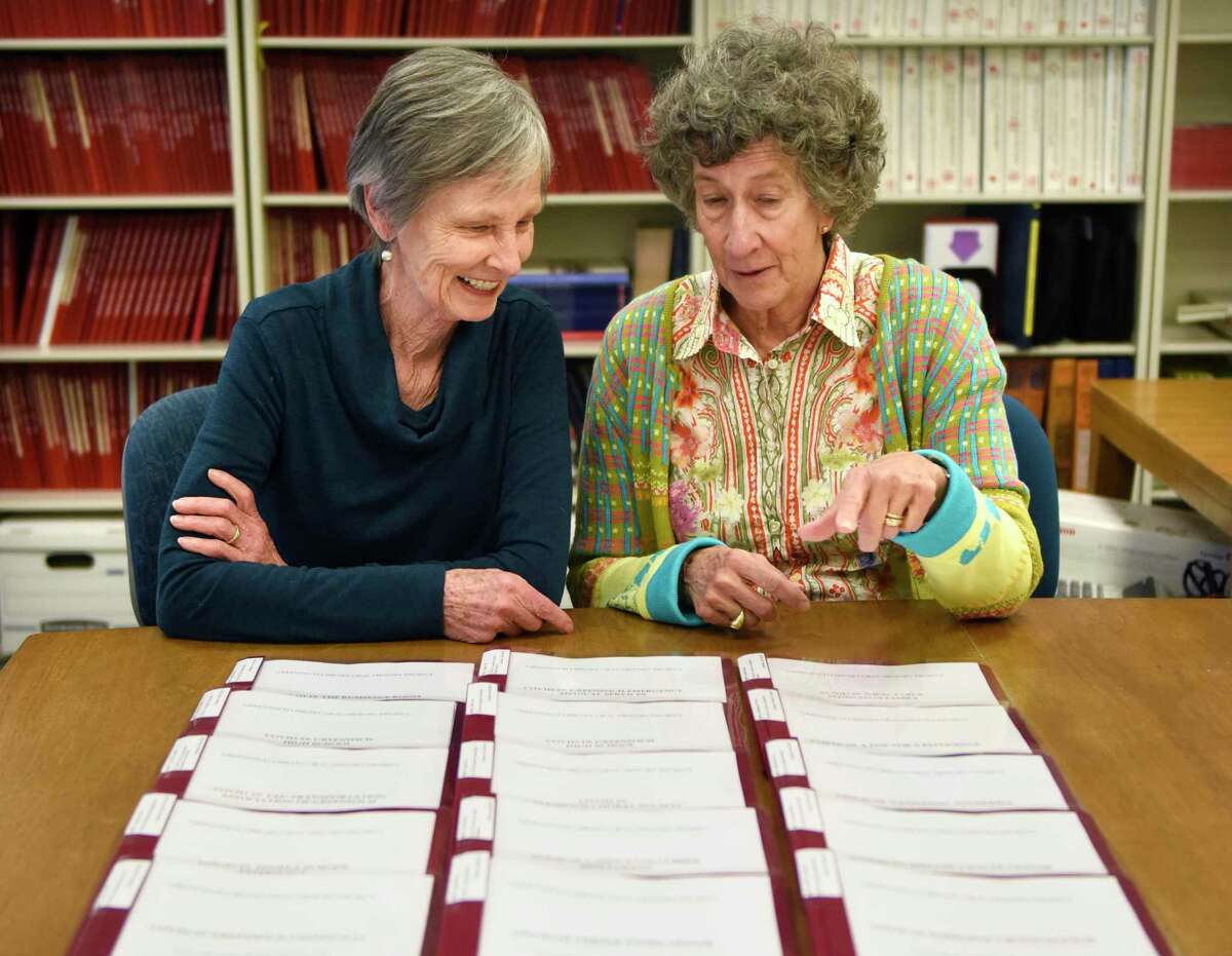 Two volunteers of the Oral History Project looking at transcripts displayed on a table