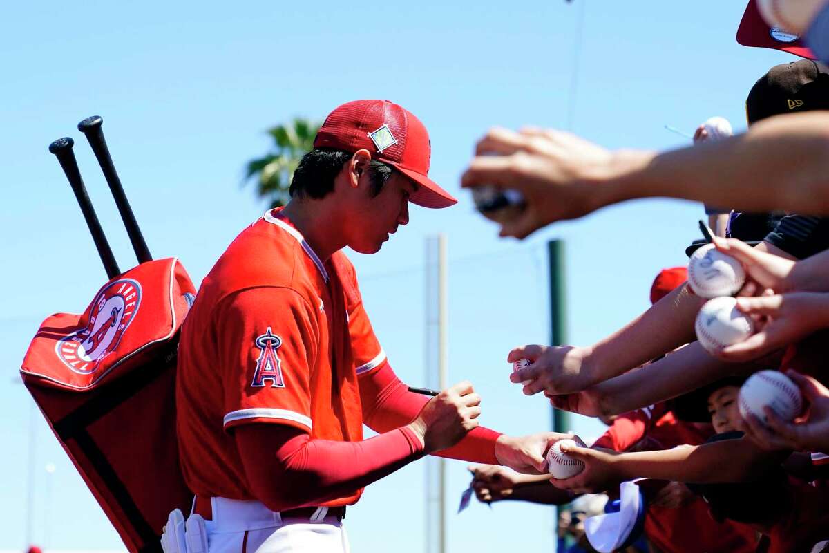 Los Angeles Angels' Shohei Ohtani, of Japan, signs autographs for fans prior to the team's spring training baseball game against the Chicago Cubs on Thursday, March 24, 2022, in Tempe, Ariz. (AP Photo/Ross D. Franklin)