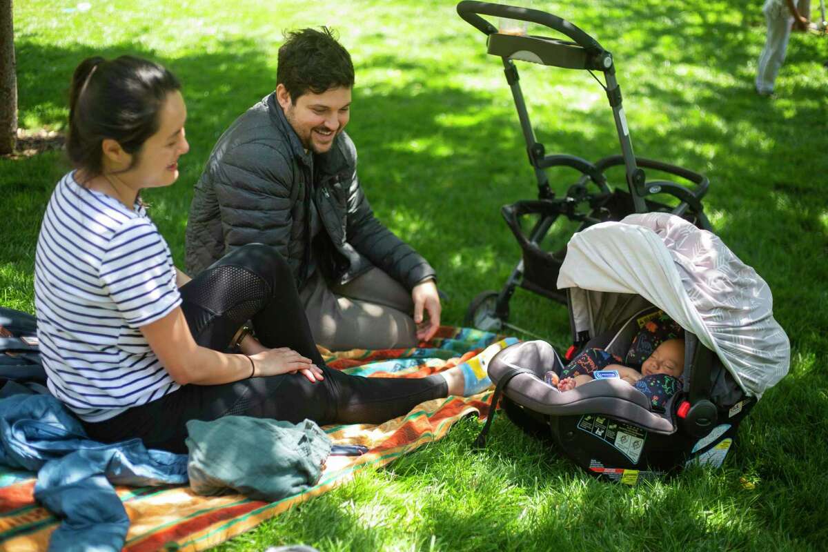 TJ Nguyen, left, and Brian Bernstein, right, enjoy being on parental leave and spending time with their new born baby, Leo, at the Salesforce park in downtown San Francisco, Calif on June 15, 2021.