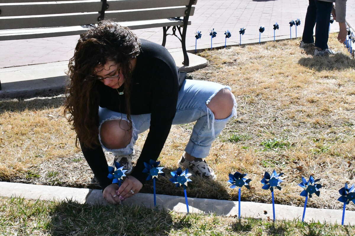 Volunteers place blue pinwheels in the sidewalks of Millennium Park in downtown Plainview as a part of the annual Go Blue event on Friday, April 1, 2022. 