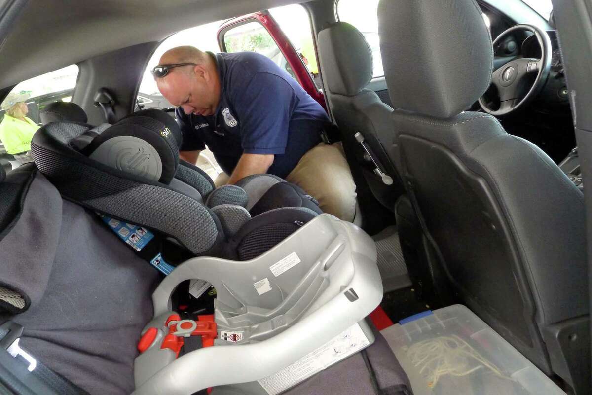 Police Sgt. Dan Contento installs a car seat during Albany County’s annual child safety seat check in Colonie N.Y., in this 2012 photo.