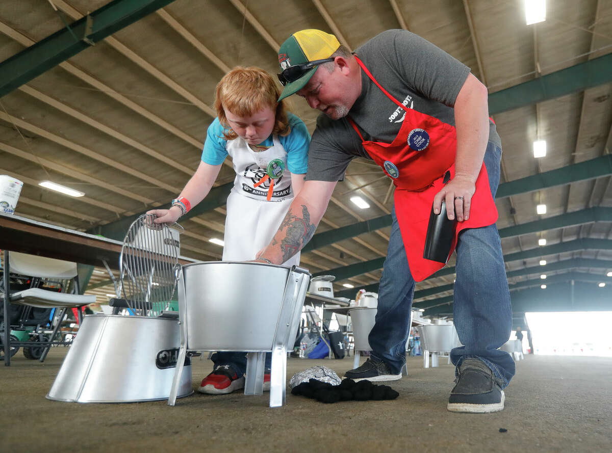 JJ Rutherford, right, shows his son, Ranger, how to stack charcoal as 50 kids took part in the inaugural KidzQ barbecue cook off during the Montgomery County Fair and Rodeo, Saturday, April 2, 2022, in Conroe.