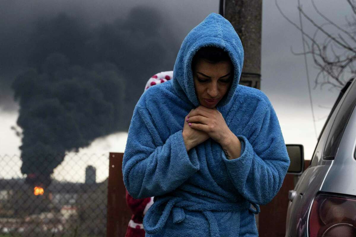 A woman walks as smoke rises in the air in the background after shelling in Odesa, Ukraine, Sunday, April 3, 2022.