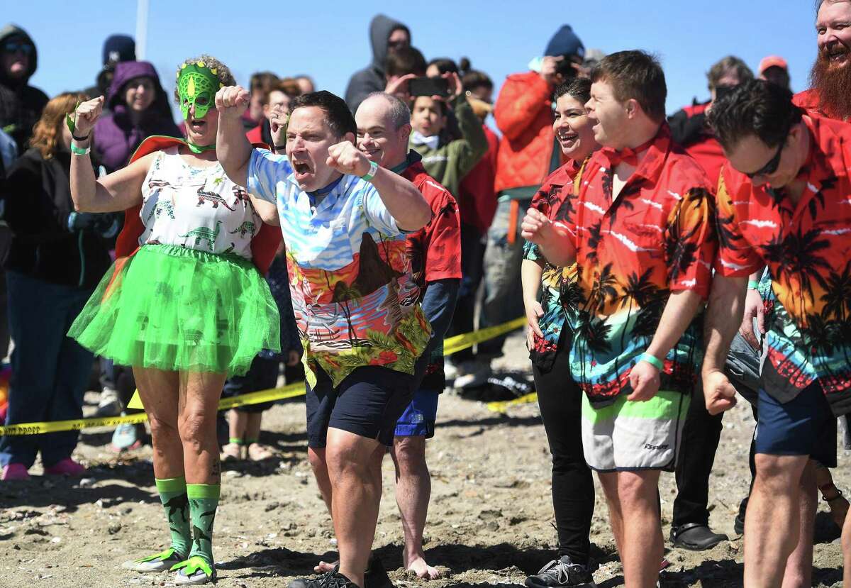 Lee Reid, second from left, of Westport, gets excited as he and Our Vision group members prepare to race into the Sound during the annual Penguin Plunge at Jennings Beach in Fairfield on Saturday.