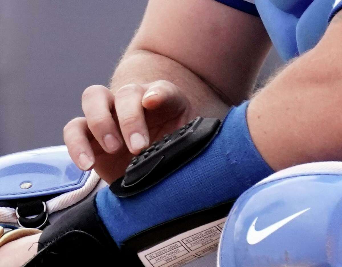 Kansas City Royals catcher Cam Gallagher uses a wrist-worn device that lets catchers send electronic encrypted signs to their pitchers.