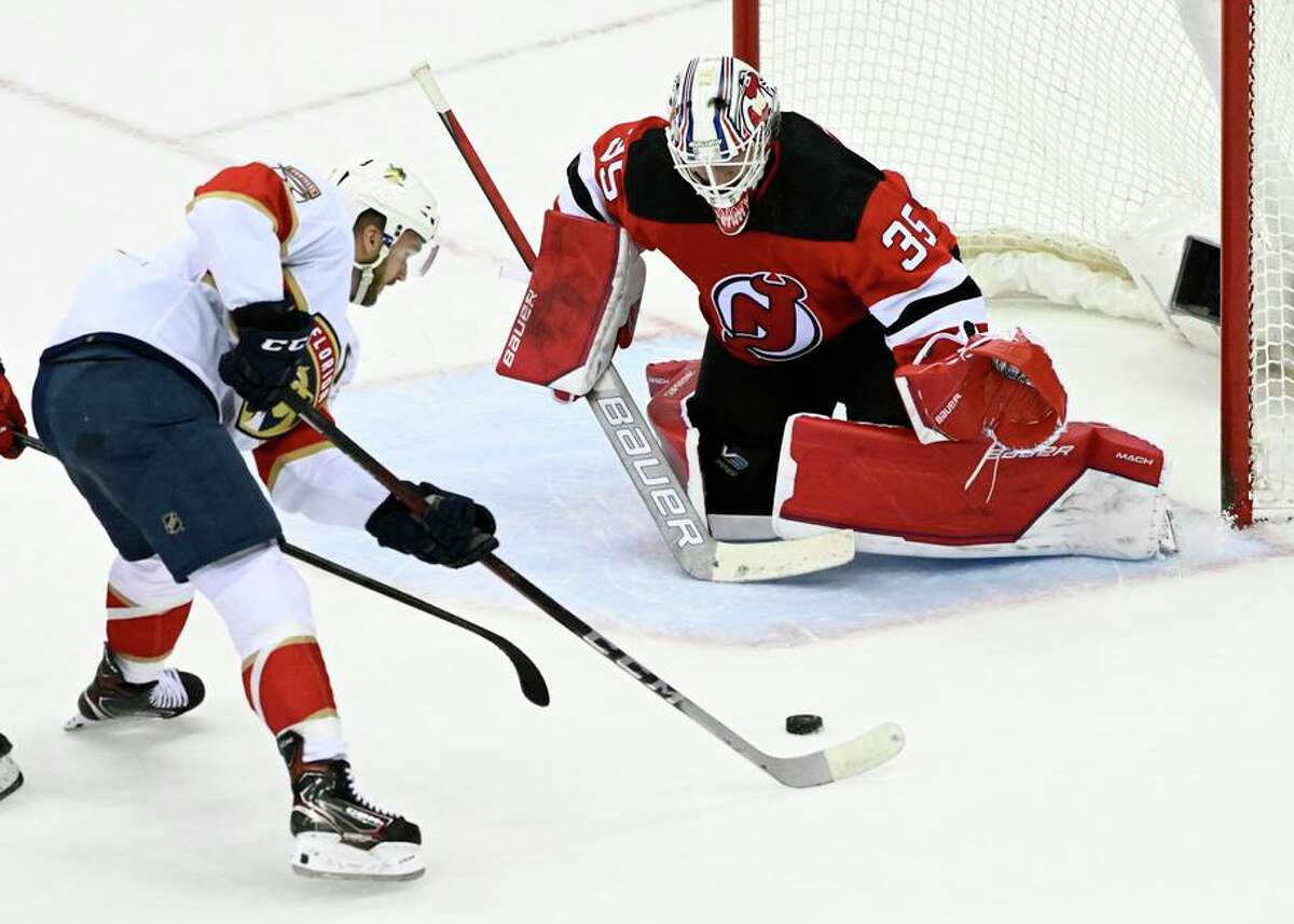 The Panthers’ Jonathan Huberdeau skates in on the Devils’ Andrew Hammond during the overtime period of an NHL hockey game Saturday, April 2, 2022, in Newark, N.J. The Panthers won 7-6 in overtime. (AP Photo/Bill Kostroun)