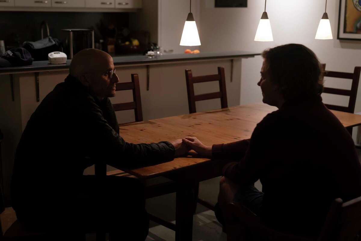 Harry Bruell, left, and wife, Jenny, hold hands while chatting in their home in Santa Barbara, Calif., Wednesday, March 9, 2022. Their daughter, Taya, killed herself when she was 14. Taya was a bright, precocious student who had started struggling with mental health issues at about 11, according to her father. At the time, the family lived in Boulder, Colorado where Taya was hospitalized at one point for psychiatric care but kept up the trappings of a model student.