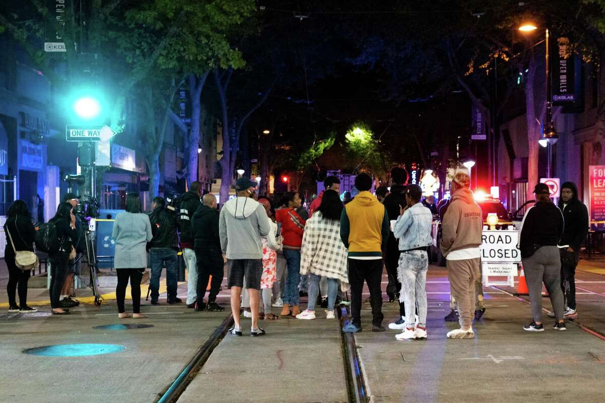 Onlookers gather at a crime scene of a mass shooting in downtown Sacramento where 6 people killed and over a dozen were wounded on April, 3, 2022.