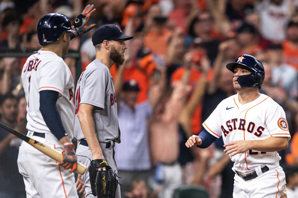 Jose Altuve of the Houston Astros reacts with Carlos Correa after scoring as Boston's Chris Sale looks on during the first inning of game one of the 2021 American League Championship Series at Minute Maid Park on October 15, 2021 in Houston,
