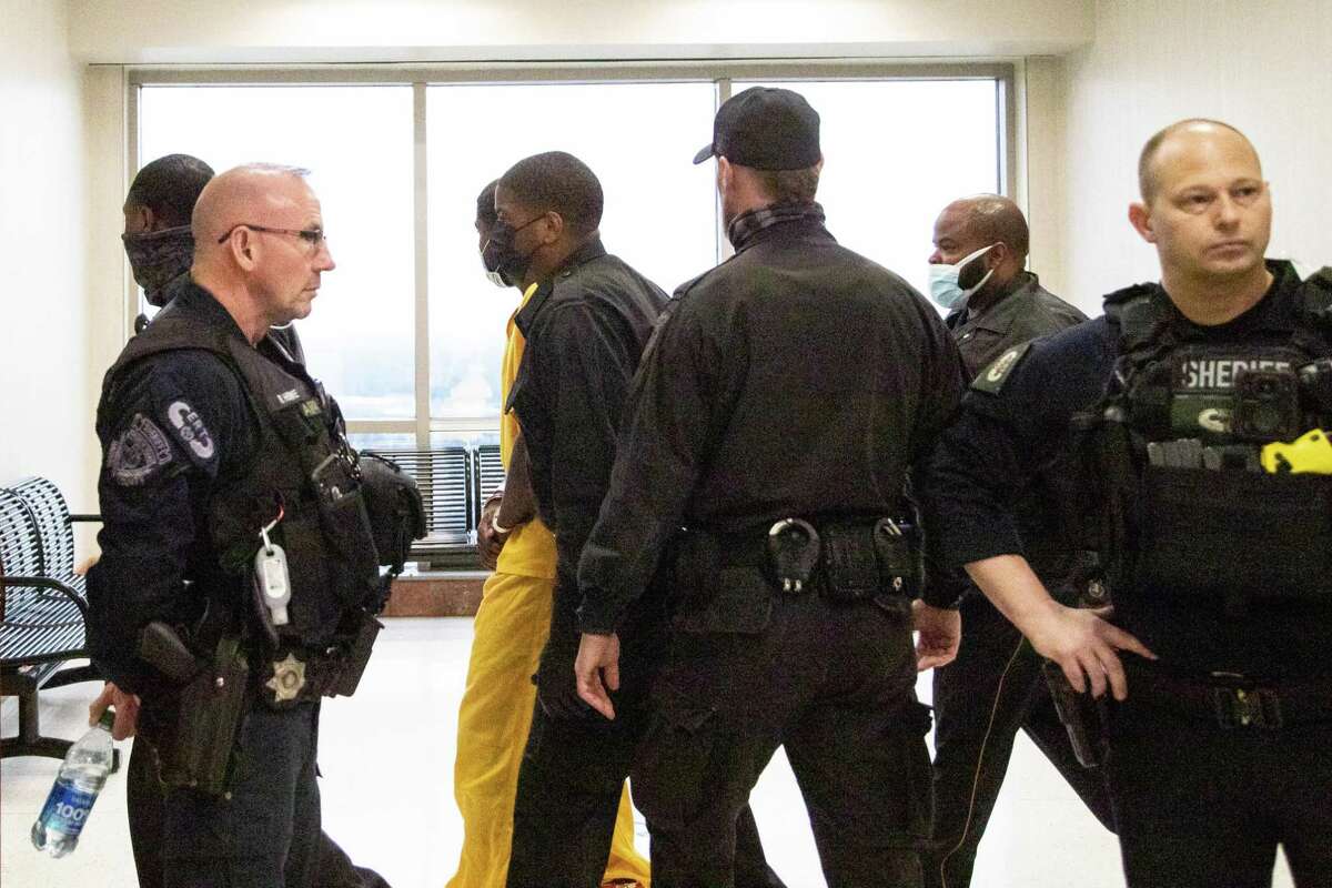 Wearing a yellow jumpsuit, Joshua Stewart, 23, suspect in the killing of off-duty Harris County sheriff’s deputy Darren Alméndarez is walked to the Harris County 177th District Court for his court appearance, Monday, April 4, 2022, in Houston.