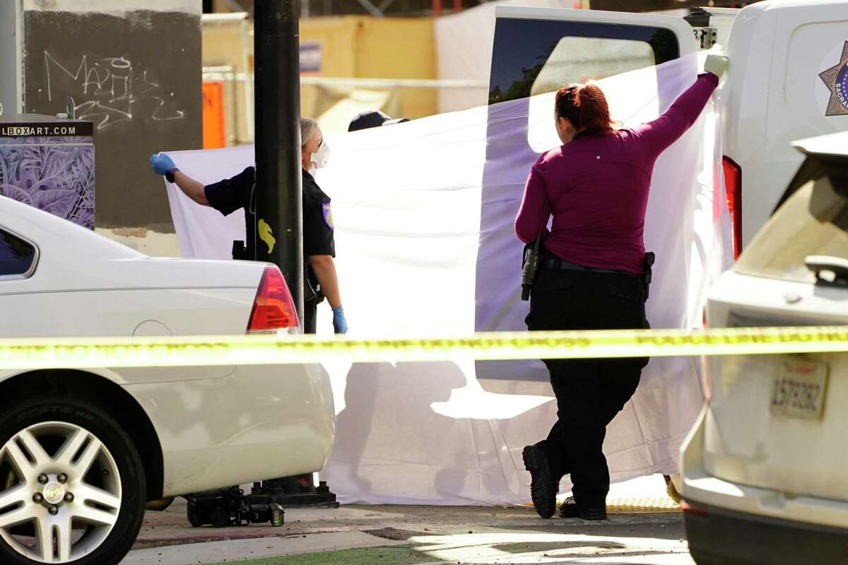 A sheet is used to block the view as the body of one of victims killed in a mass shooting in Sacramento is loaded into a coroners van on Sunday.