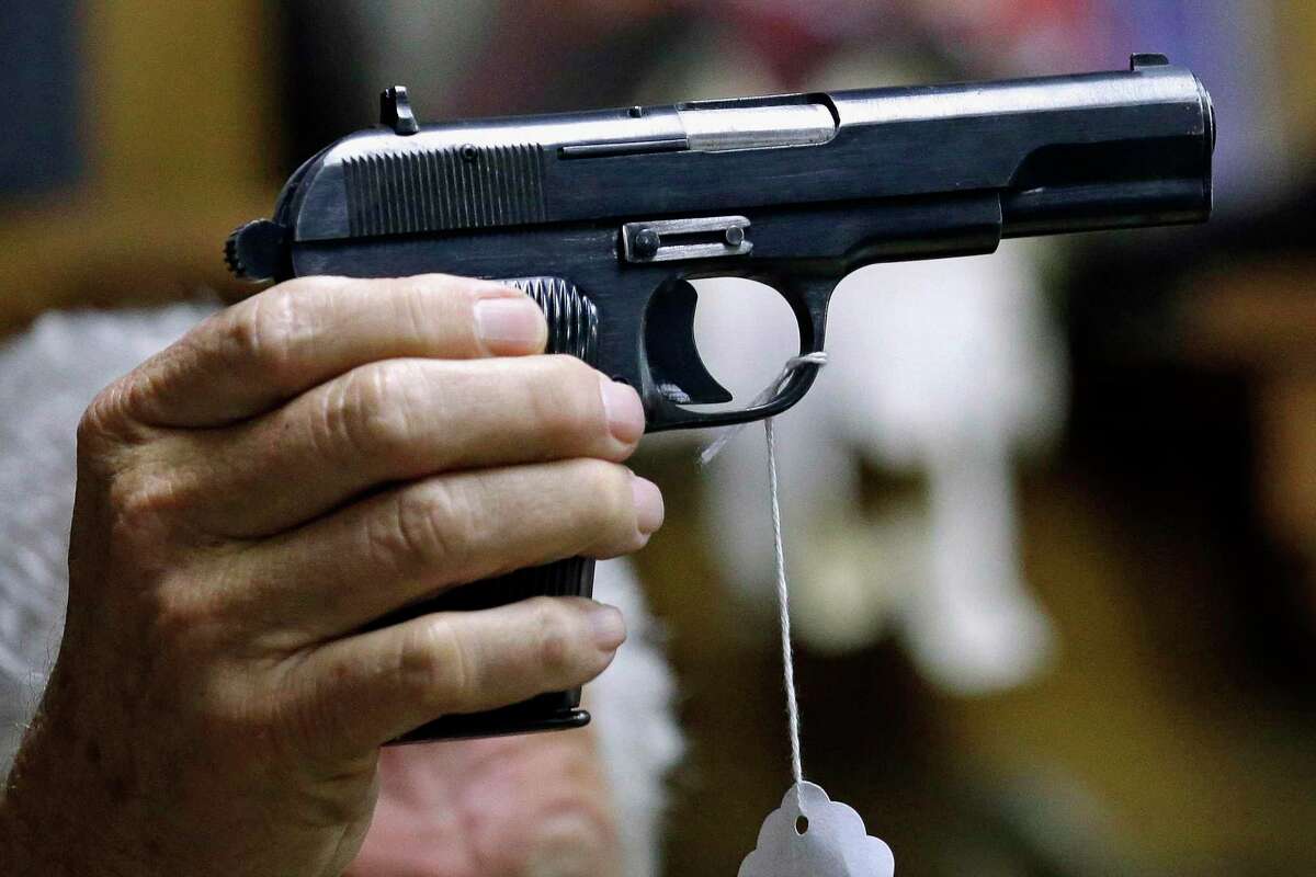 A sales clerk holds a pistol at a Washington auction. A new study from Stanford suggests people who live with handgun owners are murdered at more than twice the rate of people who live in homes without such firearms.