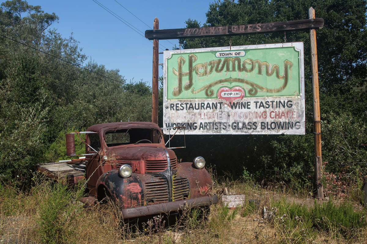 An old rusted Dodge flatbed truck sits in the weeds at the entrance to this artist community near Harmony, Calif.