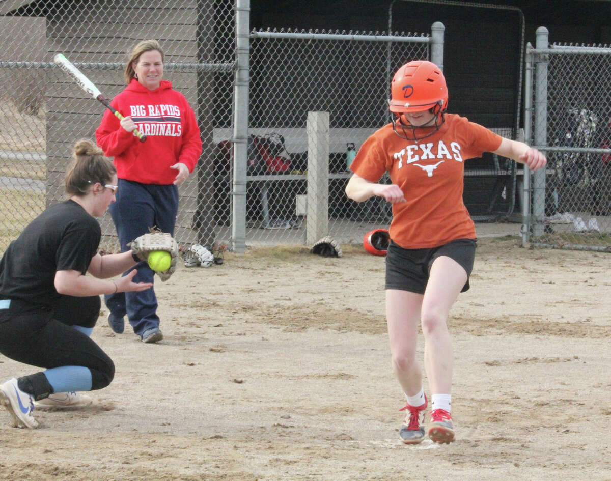 Rylie Haist (left) makes the catch at home while coach Dawn Thompson (second from left) watches during a recent Big Rapids practice.