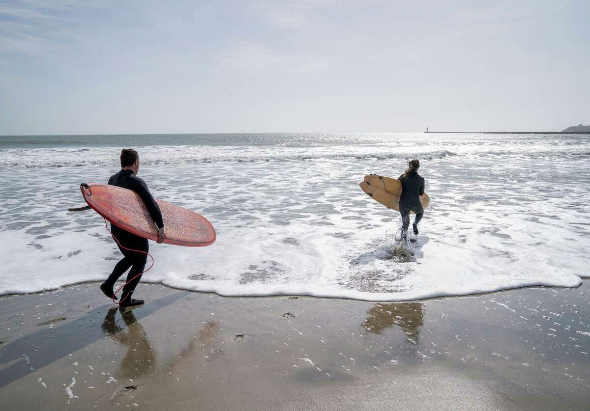 Surfers head into the water Sunday at Surfers Beach near Half Moon Bay.