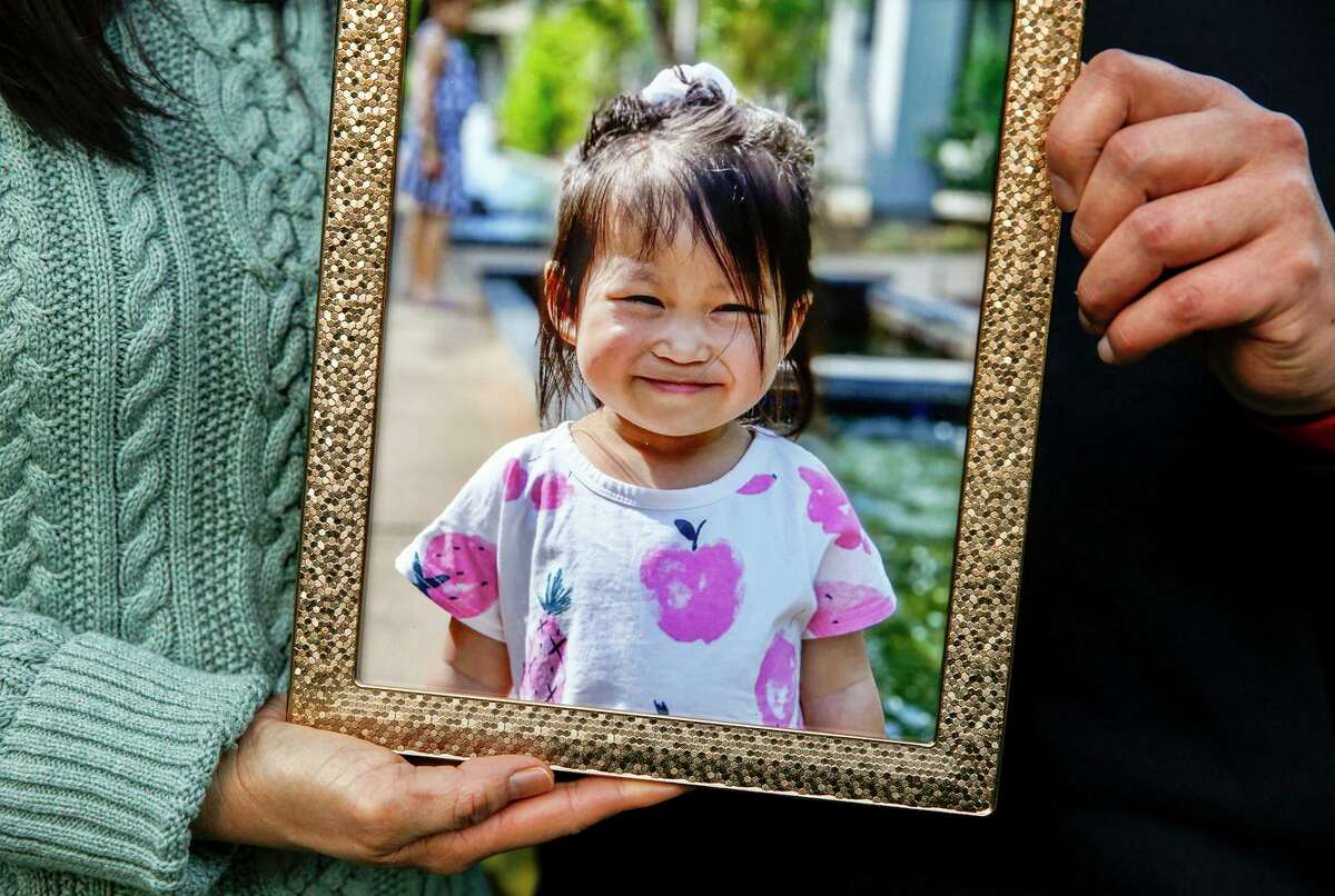 The hands of Truc-Co and Tom Jong hold a photo of their two-year-old daughter Ailee while standing for a portrait near their home in Danville, Calif. 