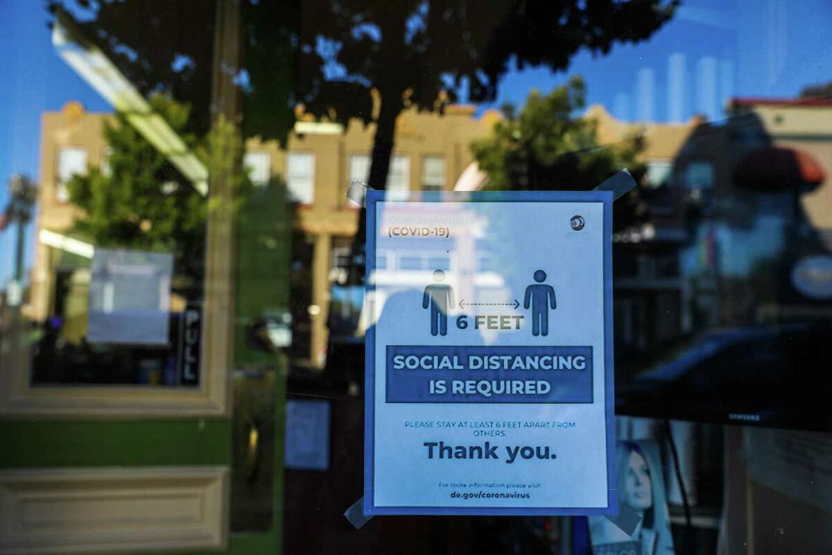 A poster detailing social distancing rules is displayed at a business on Park St. in June of 2021, in Alameda, Calif.