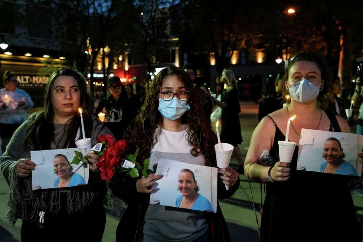 Kristin Lopez (left) and Monica Madrid hold photos of Melinda Davis at Monday’s candlelight vigil.