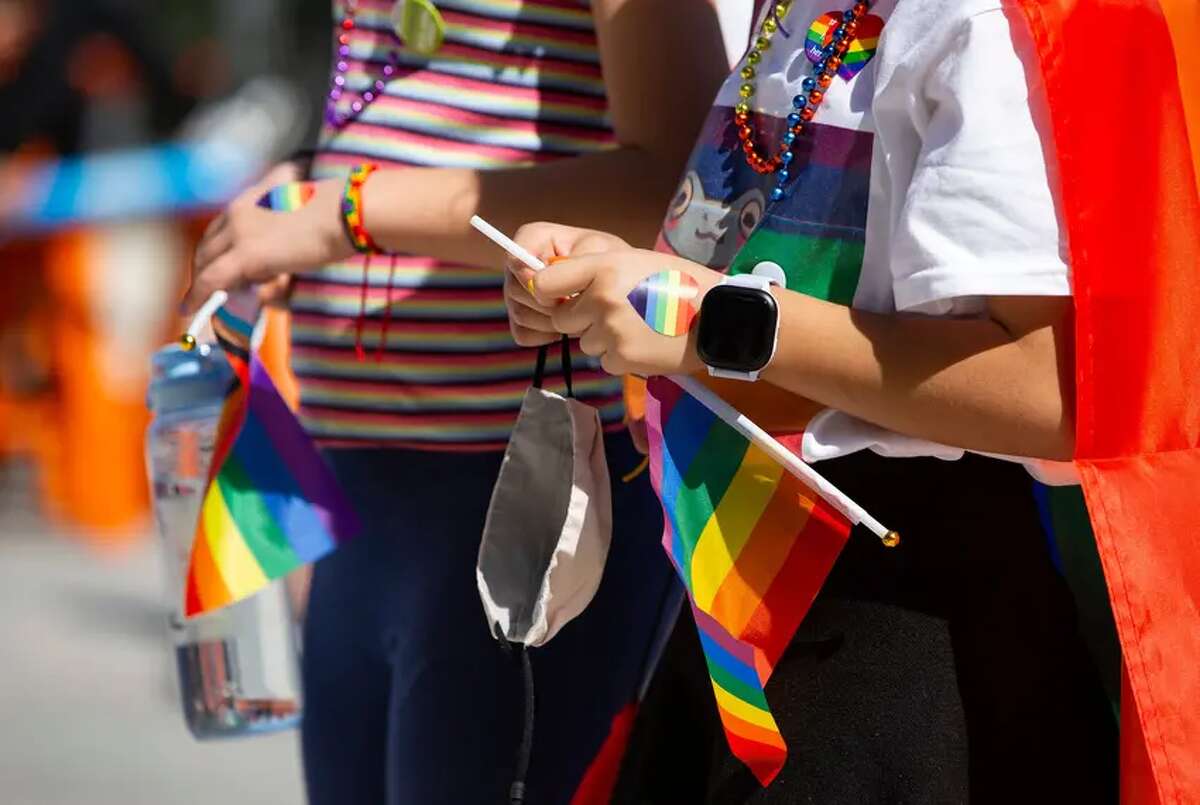 Kids hold flags and wear heart stickers and beads at the Austin Independent School District’s “Pride Out!” party in Austin last month. Lt. Gov. Dan Patrick wants a Texas law similar to Florida legislation limiting classroom lessons about LGBTQ people. 