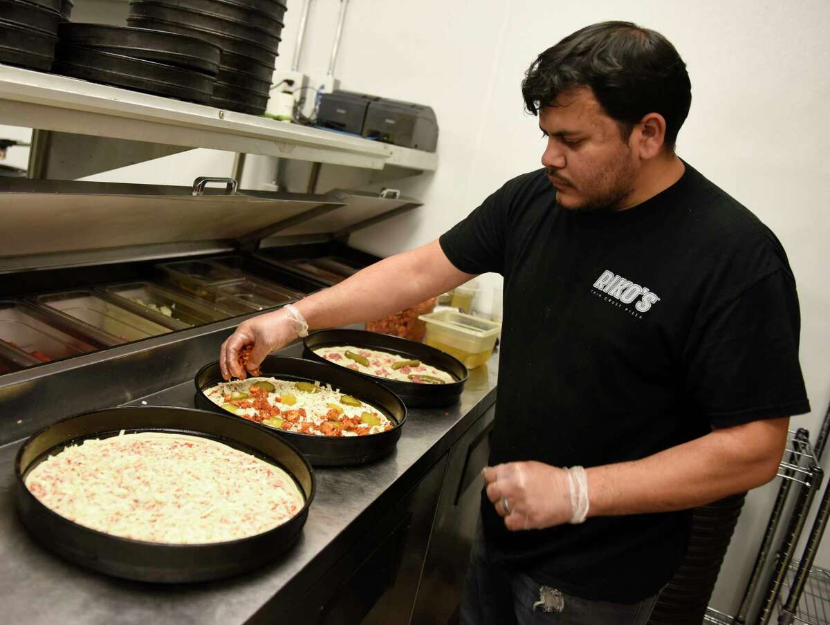 Eduardo Sanchez makes pizzas during the opening day at Riko's Pizza in Stamford, Conn. Tuesday, April 5, 2022. Riko's Pizza opened a new location at 2010 West Main St. in Stamford on Tuesday. The menu features a variety of thin crust pizzas, including the famous hot oil pizza, as well as salad pizzas, hot wings, and a full bar with an innovative cocktail menu.