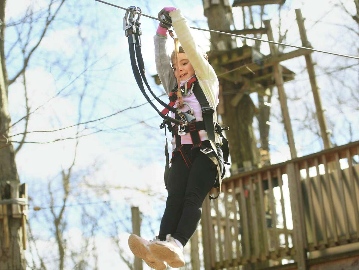 Livia Clark, 7, of Mendham, NJ, rides a zip line during her first ever ropes course with her family during opening day at The Adventure Park at the Discovery Museum in Bridgeport, Conn., on Friday, April 1, 2022.