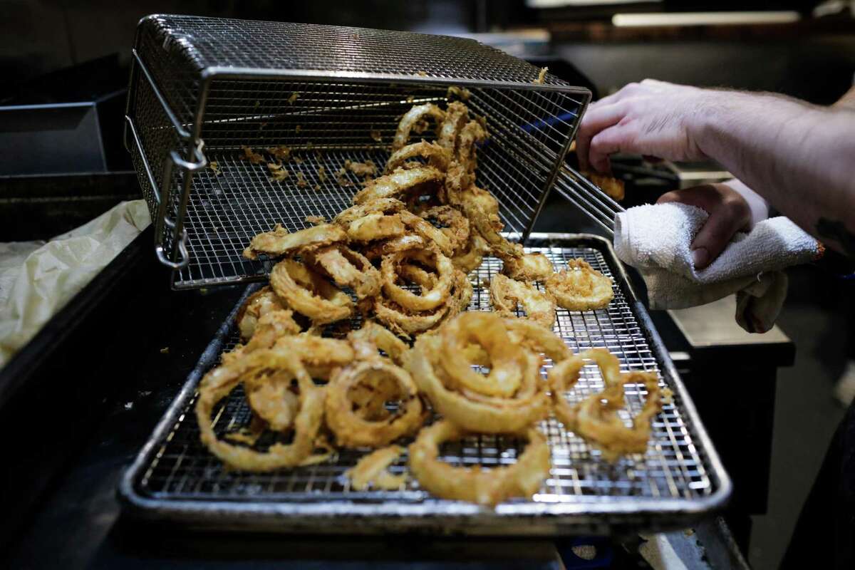 Fried onion rings are moved from the fryer to a tray while Chef Jeff Hayden prepares the roasted beet and winter citrus salad with fried onion mousse dish at Del Popolo restaurant in San Francisco, California, on Wednesday, Feb. 8, 2017.