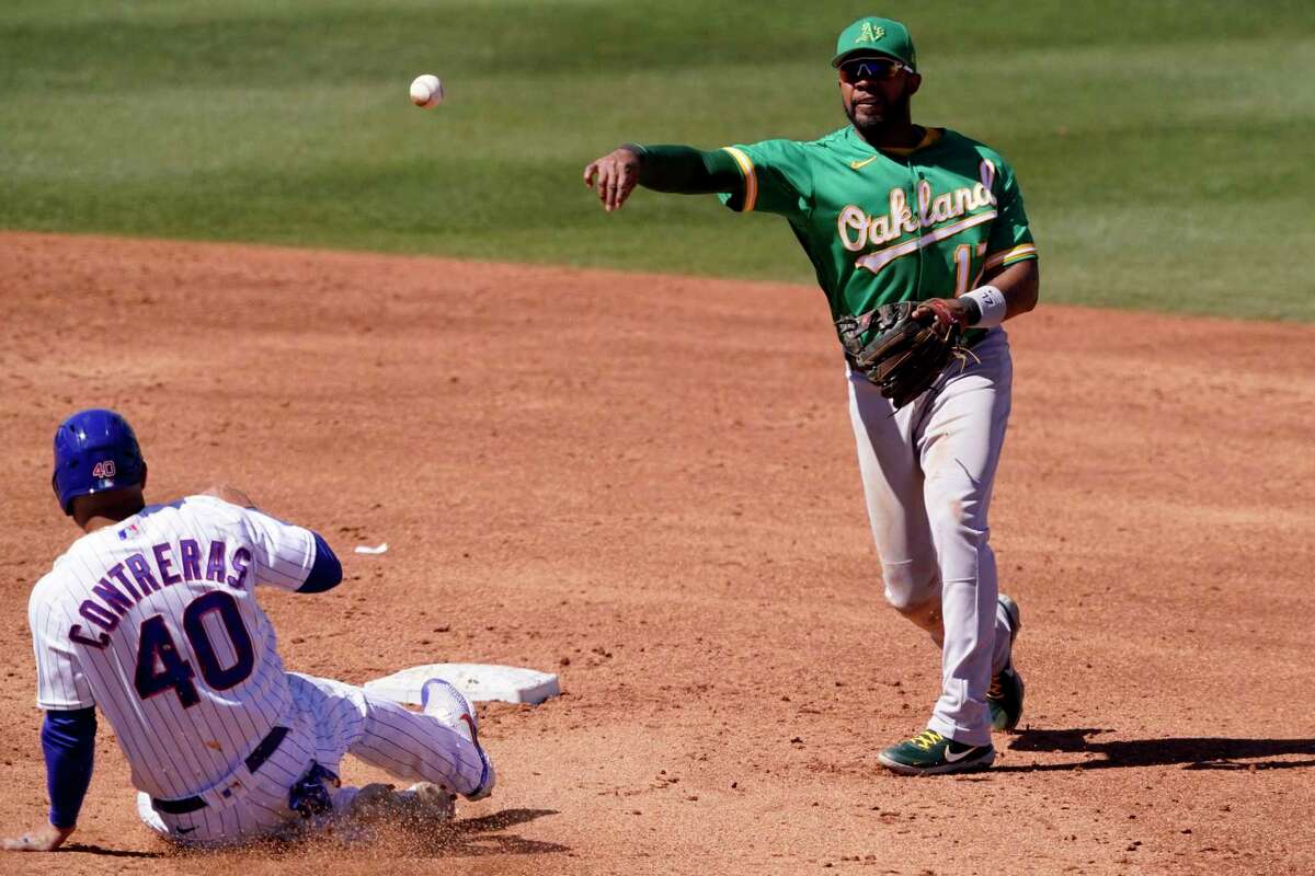 Oakland Athletics' Elvis Andrus (17) forces out Chicago Cubs' Willson Contreras (40) as he turns a double play on Ian Happ during the third inning of a spring training baseball game Wednesday, March 23, 2022, in Mesa, Ariz. (AP Photo/Matt York)