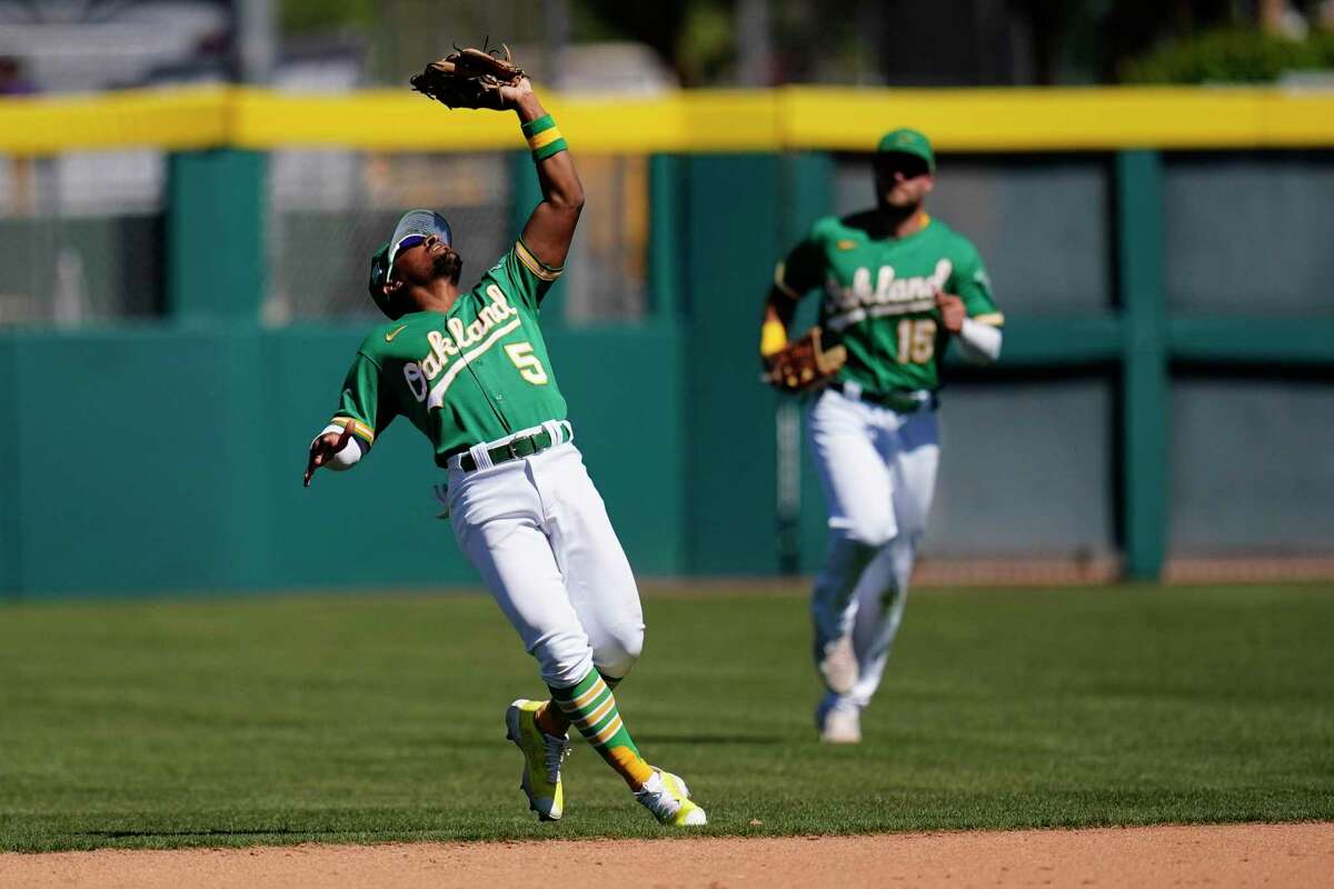 Oakland Athletics second baseman Tony Kemp (5) makes a catch on a pop fly against the Colorado Rockies as Athletics right fielder Seth Brown (15) looks on during the fourth inning of a spring training baseball game Saturday, April 2, 2022, in Mesa, Ariz. (AP Photo/Ross D. Franklin)