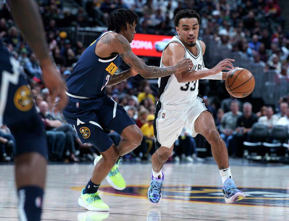 San Antonio Spurs guard Tre Jones, right, drives as Denver Nuggets guard Bones Hyland defends during the first half of an NBA basketball game Tuesday, April 5, 2022, in Denver. (AP Photo/David Zalubowski)