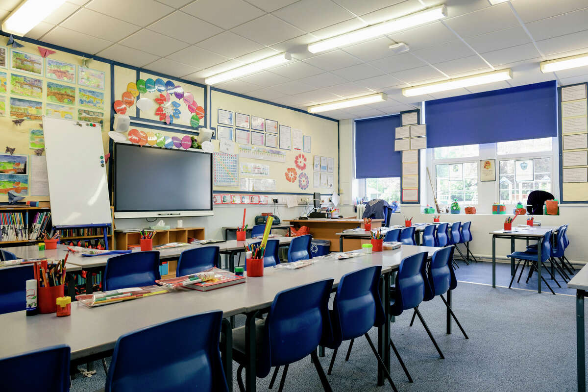 A wide angle view of an organised and tidy classroom in a school. 