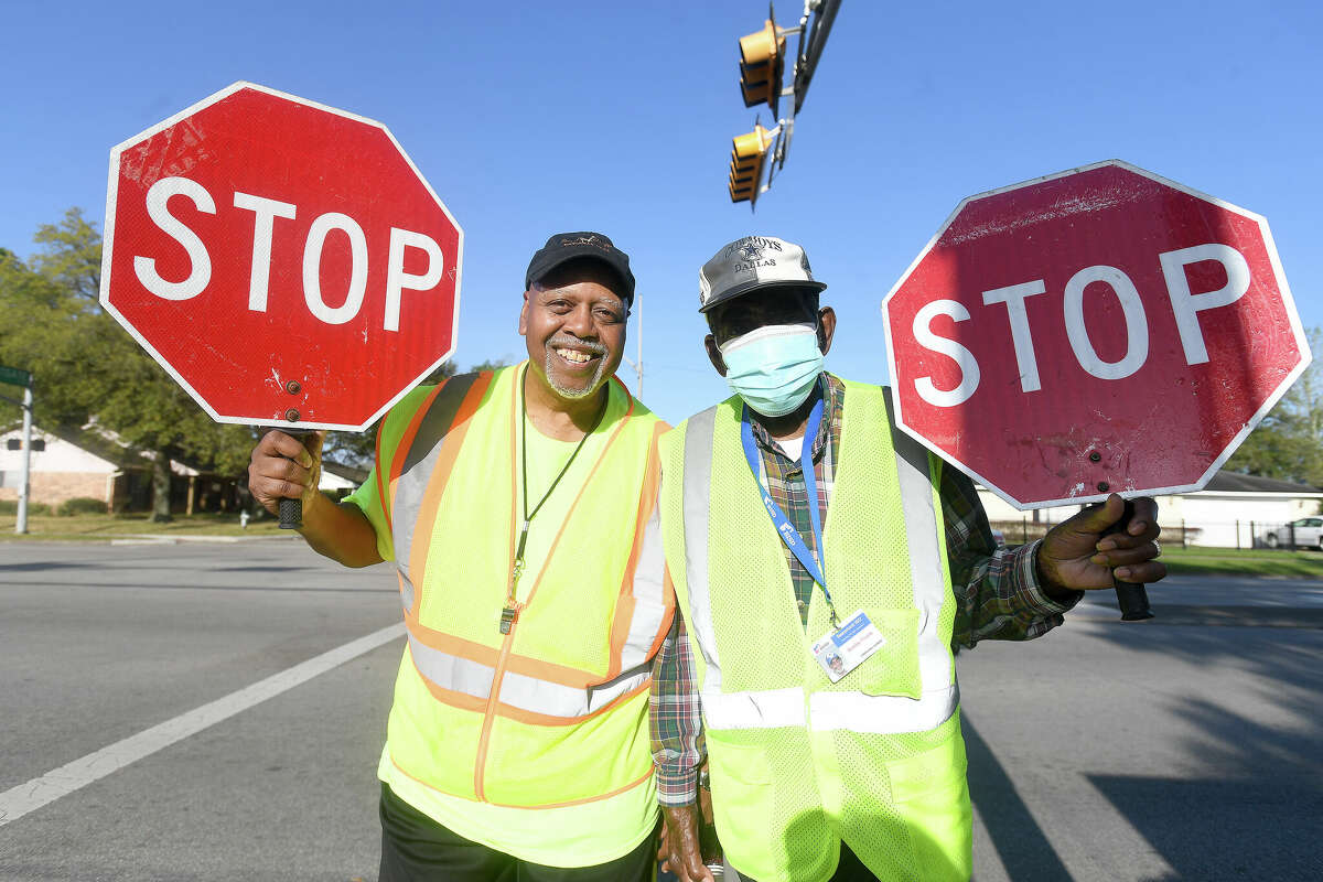 Marshall Middle School crossing guards Larry Payne (left) and Bobby Frank are renowned for spreading happiness while keeping students safe crossing their station at Dowlen and Westgate Roads. Photo made Monday, March 28, 2022 Kim Brent/The Enterprise