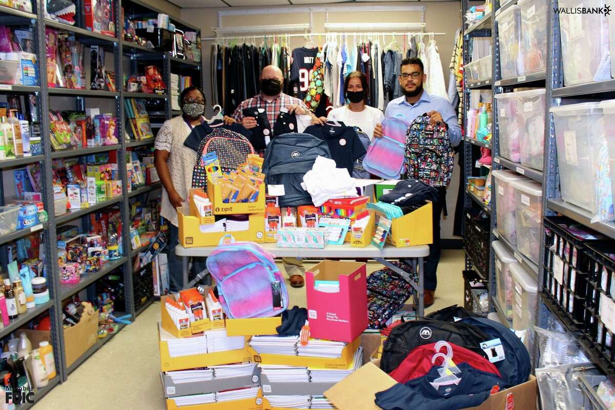 Volunteers with the Fort Bend Rainbow Room pose with supplies for children in need during a back-to-school event.