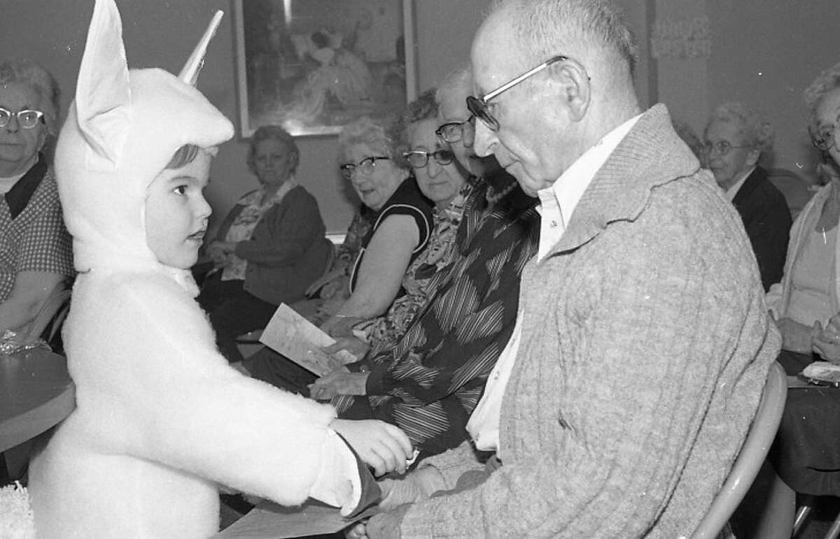 Manistee Catholic Central elementary student, Scott Veine is disguised as the Easter Bunny while presenting a gift to Joe Bassarab. Scott was one of many kindergarten, first, second and third grade MCC students who toured Century Terrace, the Manistee Medical Care Facility and Manistee Heights Care Facility yesterday to sing Easter songs and present gifts to residents. The photo was published in the News Advocate on April 8, 1982.