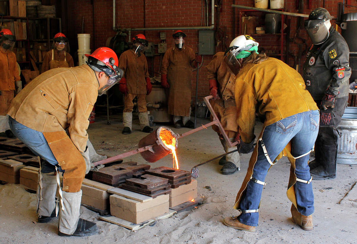 Art professor Kurt Dyrhaug, right, watches as students pour molten metal during the iron pour, March 31, on the Lamar University campus. Photo by Andy Coughlan